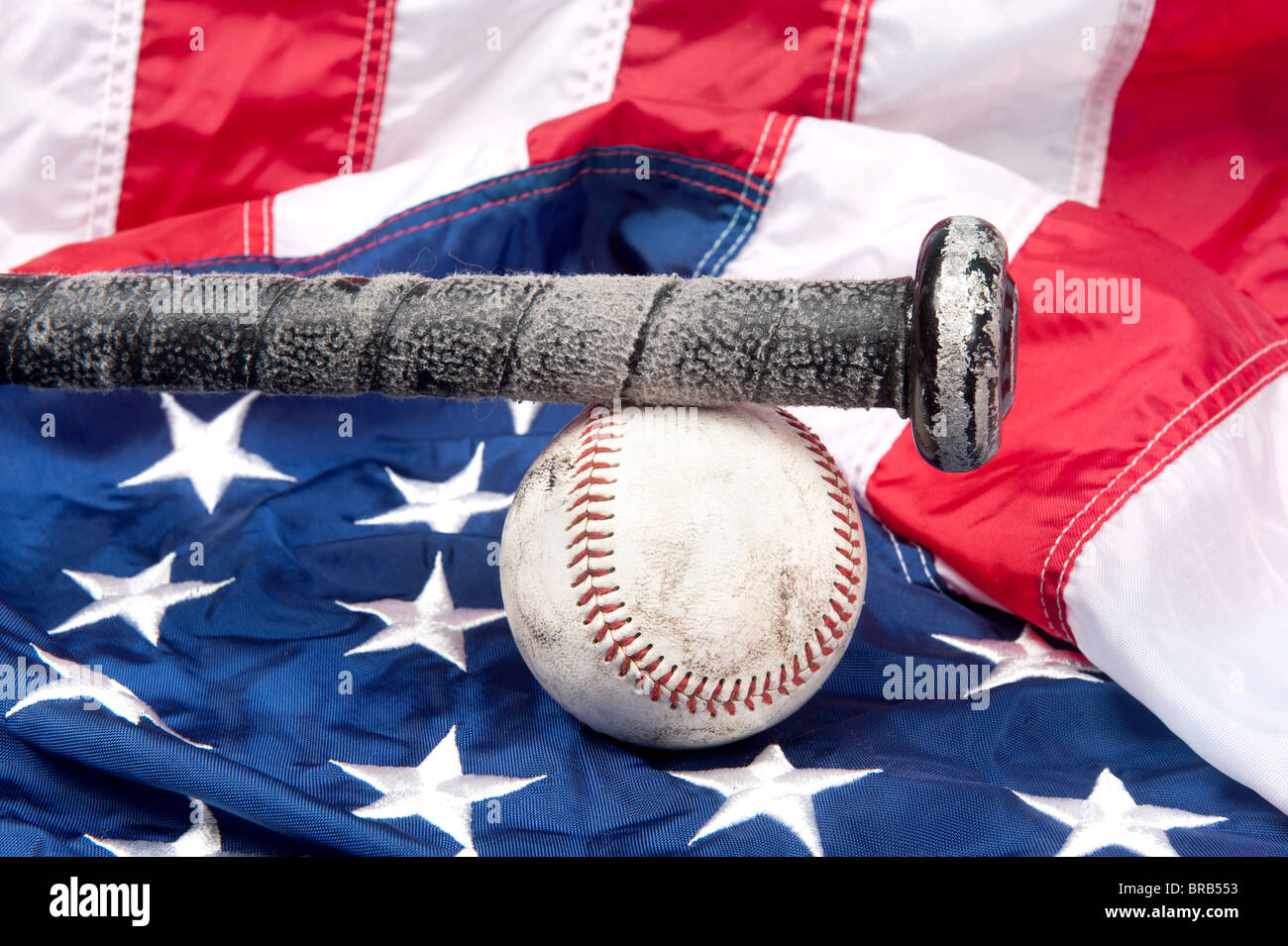 Los equipos de béisbol incluyendo un bate y una pelota de béisbol en una bandera Americana. Foto de stock