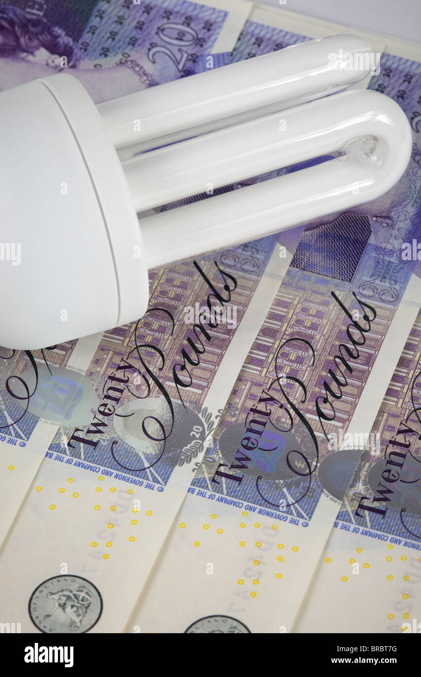Bombilla de ahorro de energía en un fondo de dinero en el Reino Unido. Foto de stock