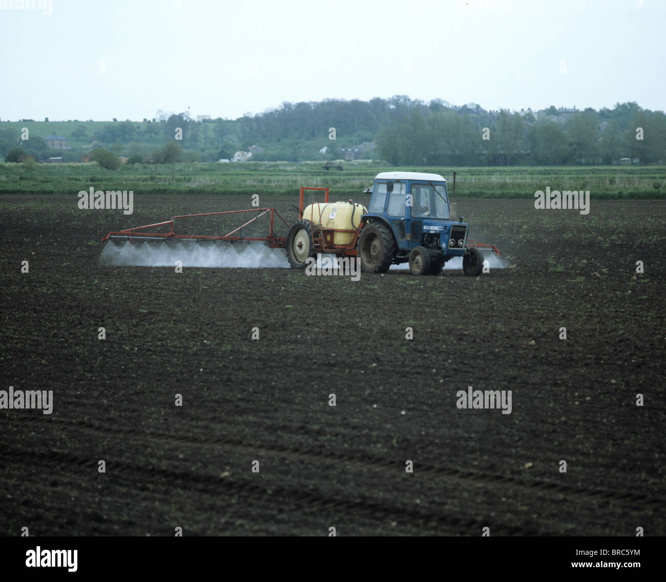 En pre-emergencia, pulverización de fenland semillero con pequeño tractor y pulverizador remolcado Foto de stock