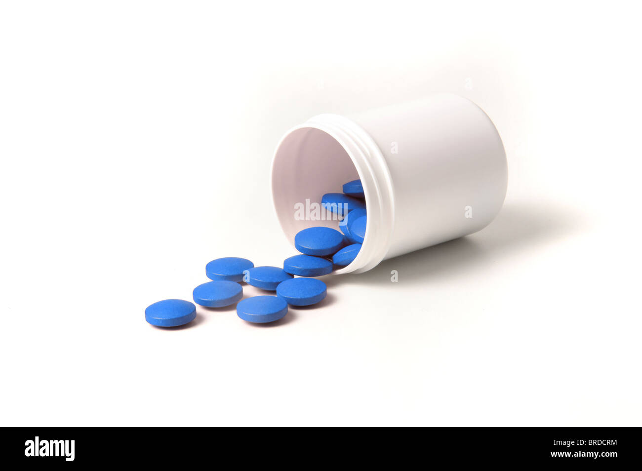 Varias pastillas de color azul y el contenedor. Todas aisladas sobre fondo blanco. Foto de stock