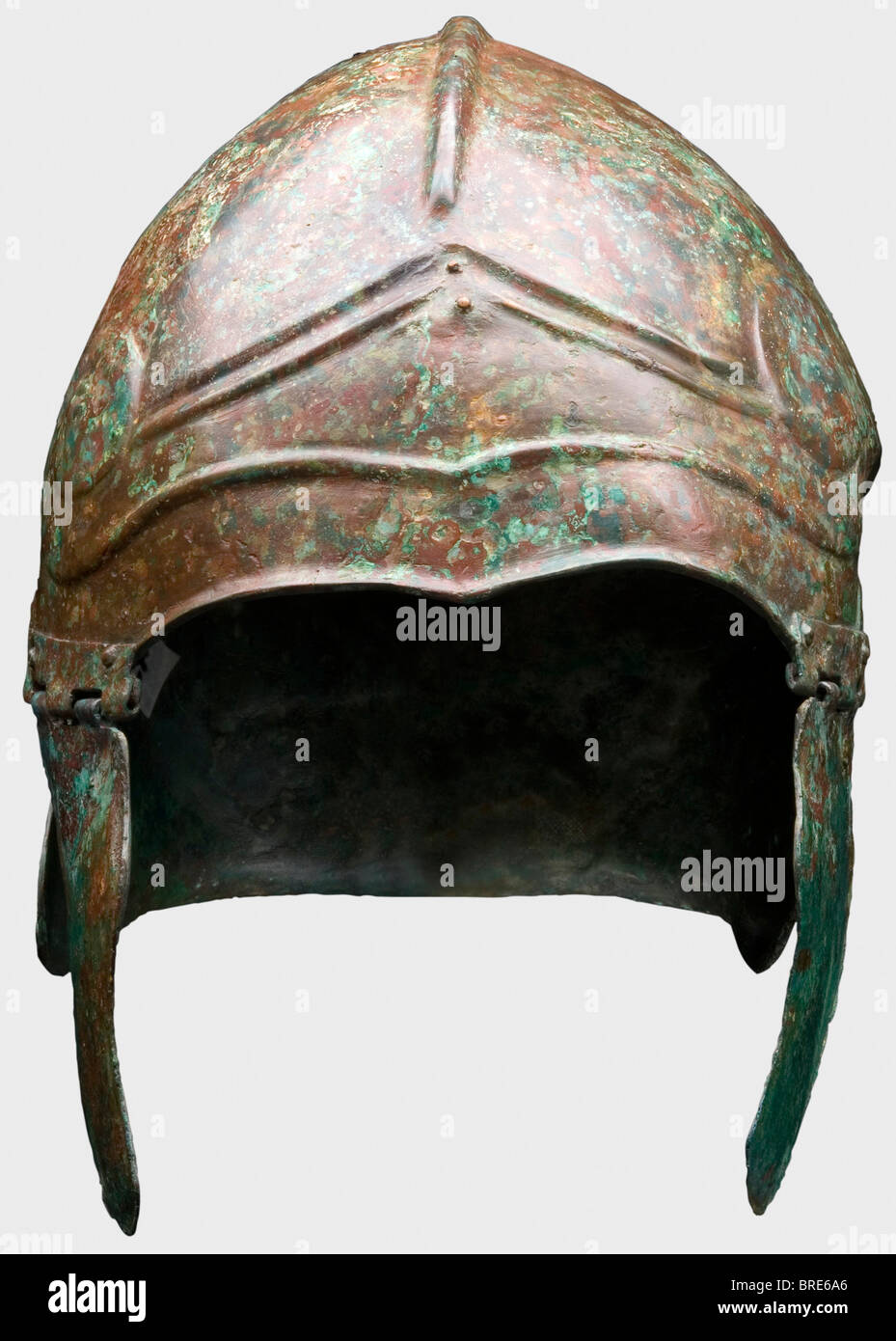 Un Casco Chancidiano, siglo IV/5 B.C., Bronce. El cráneo tiene una cresta  central y un pronunciado frontón contorneado en la frente, que termina en  una gran espiral voluta a cada lado. Protector