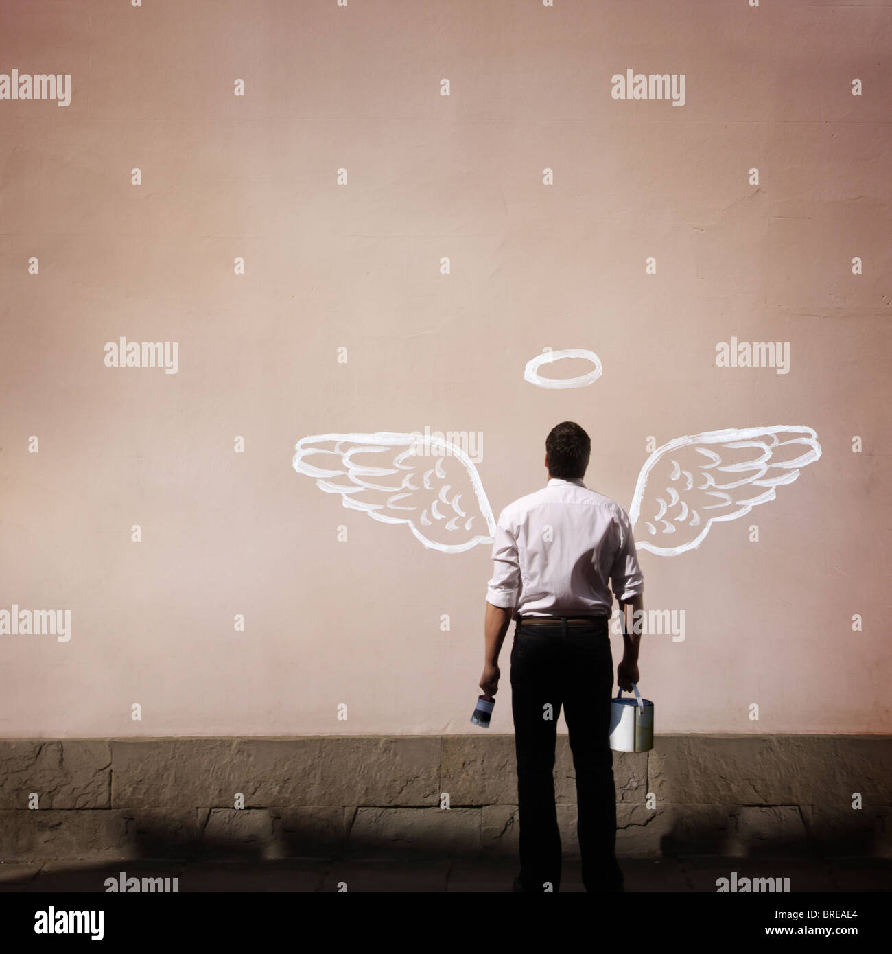 Hombre con alas de ángel pintado en una pared. Foto de stock