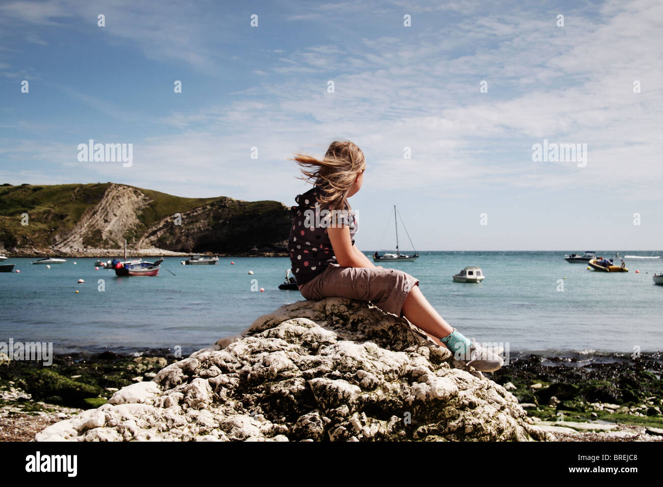 Chica sentada sobre una roca en Lulworth Cove,UK Foto de stock