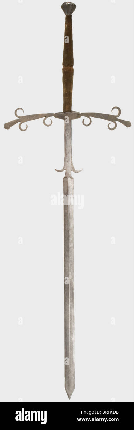 Una espada alemana de dos manos, alrededor de 1580. Hoja pesada, con  reborde en ambos lados. El ricasso largo tiene líneas decorativas  indentadas y dos ganchos curvos de casamiento. Quillons extendidos con