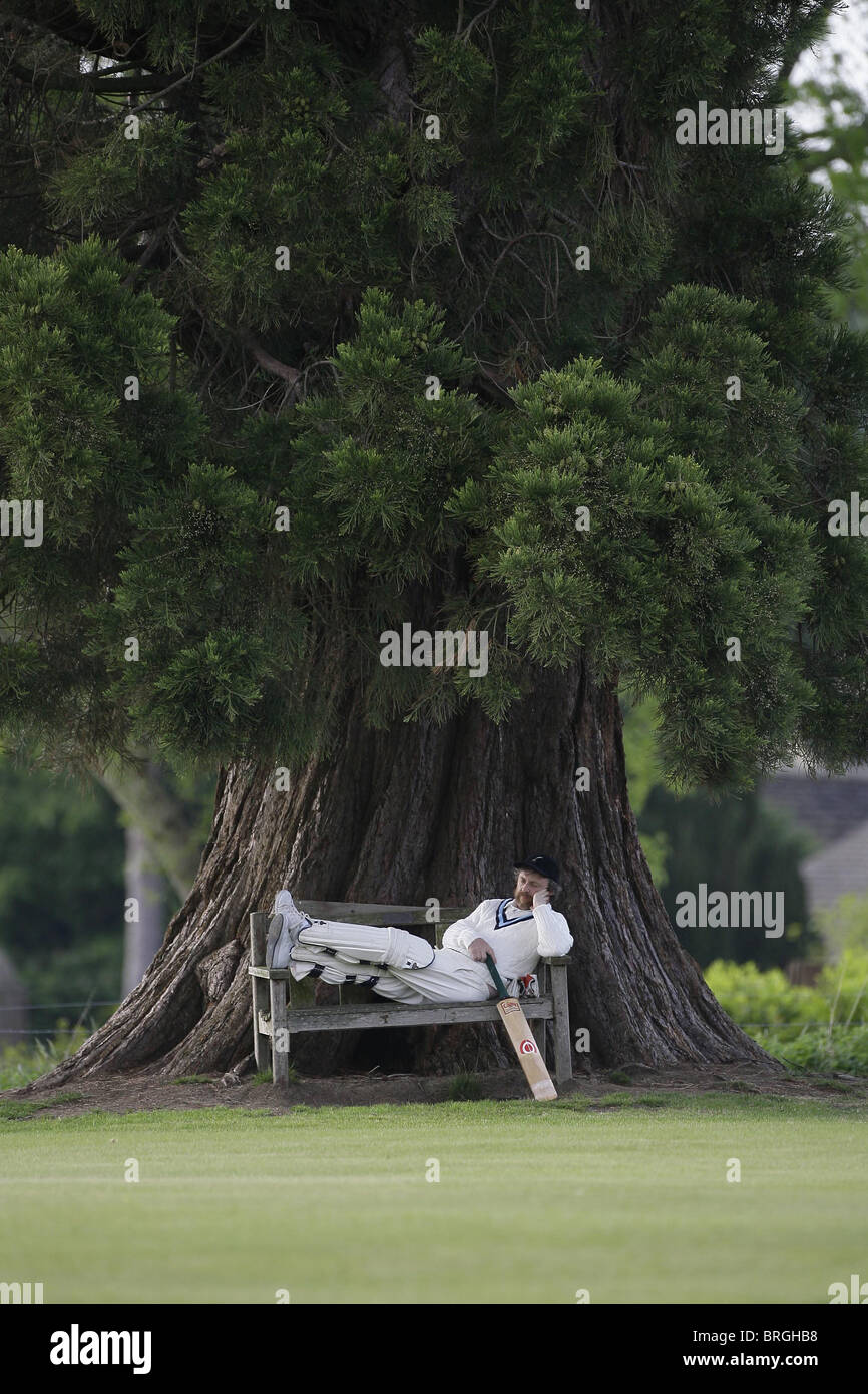 Un Cricketer relaja mientras ve una aldea coinciden. Fotografía por James Boardman. Foto de stock