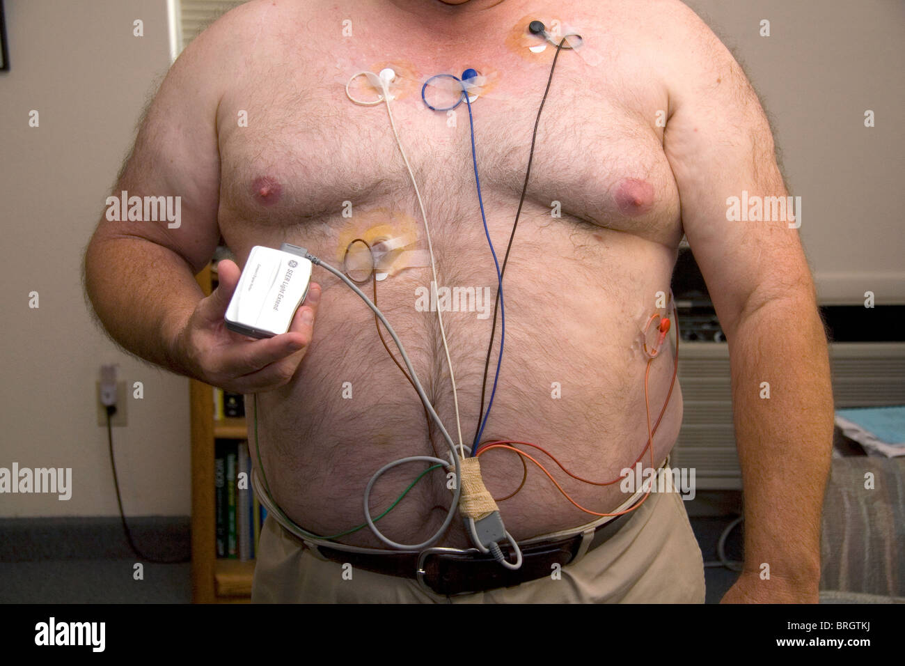 Hombre americano usando el monitor Holter se utiliza para controlar el corazón de arritmias cardíacas. Señor Foto de stock