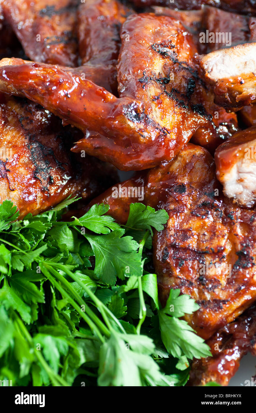 Cerca de barbacoa, alitas de pollo y costillas de cerdo con ensalada verde  Fotografía de stock - Alamy