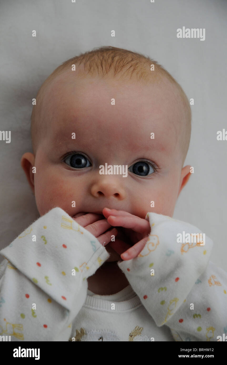 Bebé de 3 meses de edad chica chupando dedo blanco y negro con ojos azules Foto de stock