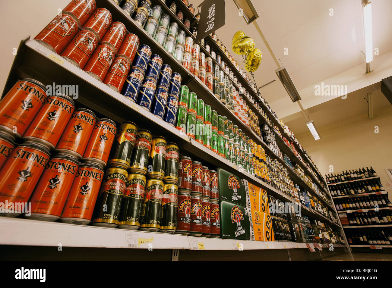 Selección de latas y botellas de cerveza para venta apilados en una estantería de supermercado, REINO UNIDO Foto de stock
