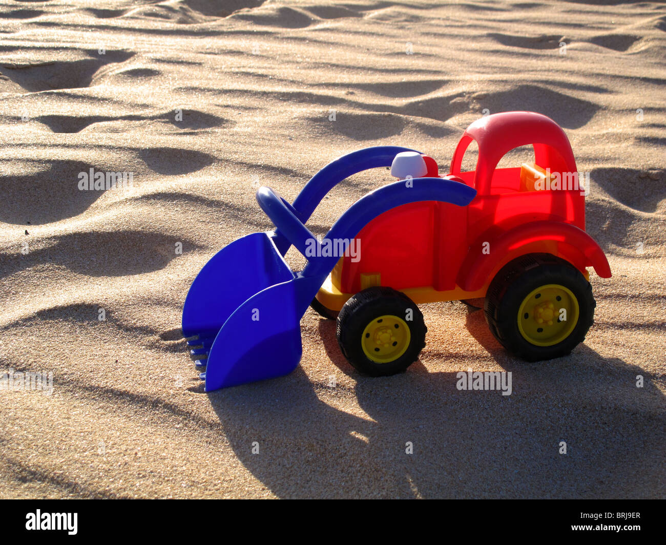 Camión de juguete de plástico de colores brillantes en la playa de arena Foto de stock