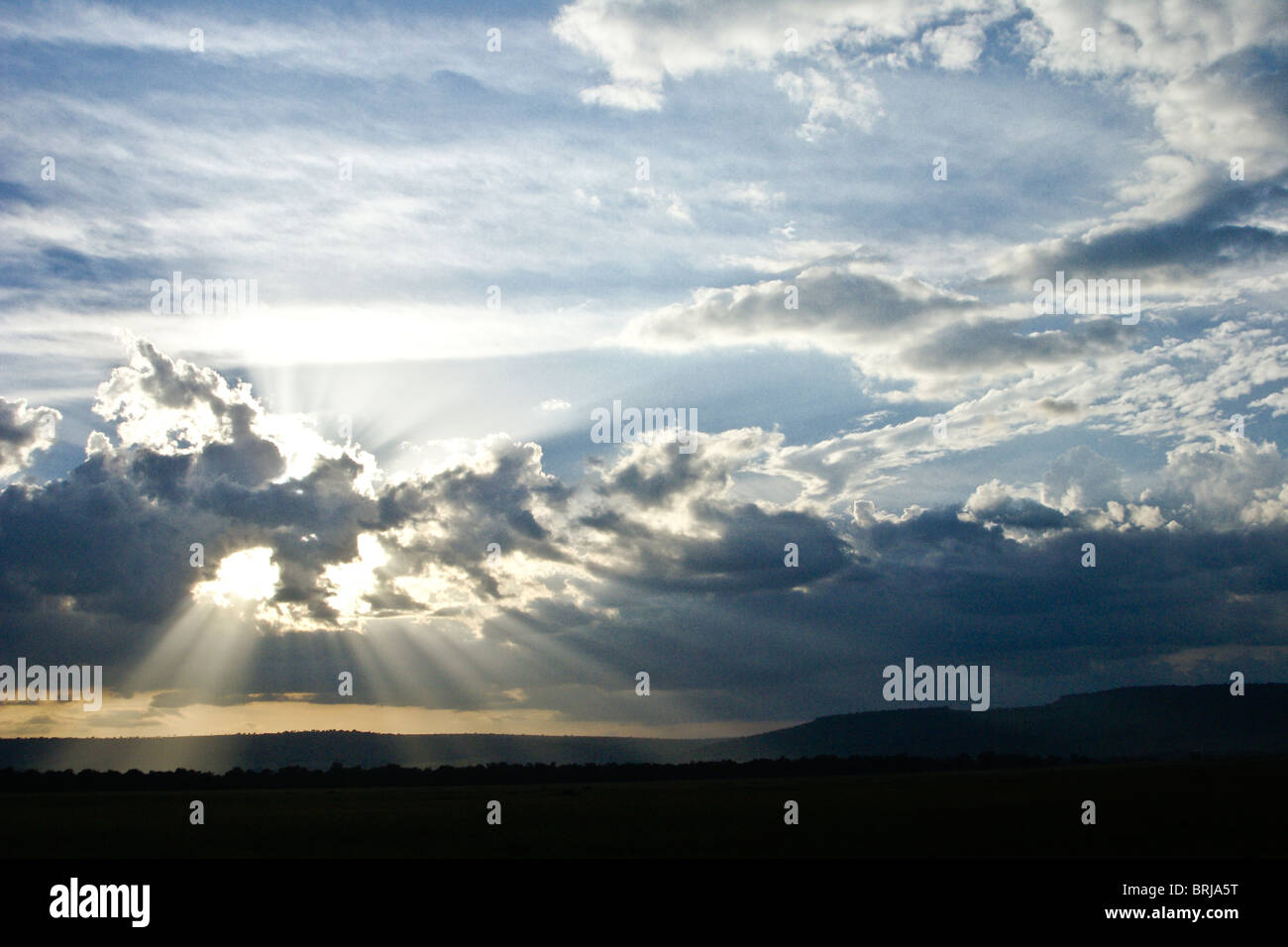 El sol detrás de las nubes (rayos crepusculares), Masai Mara, Kenya Foto de stock