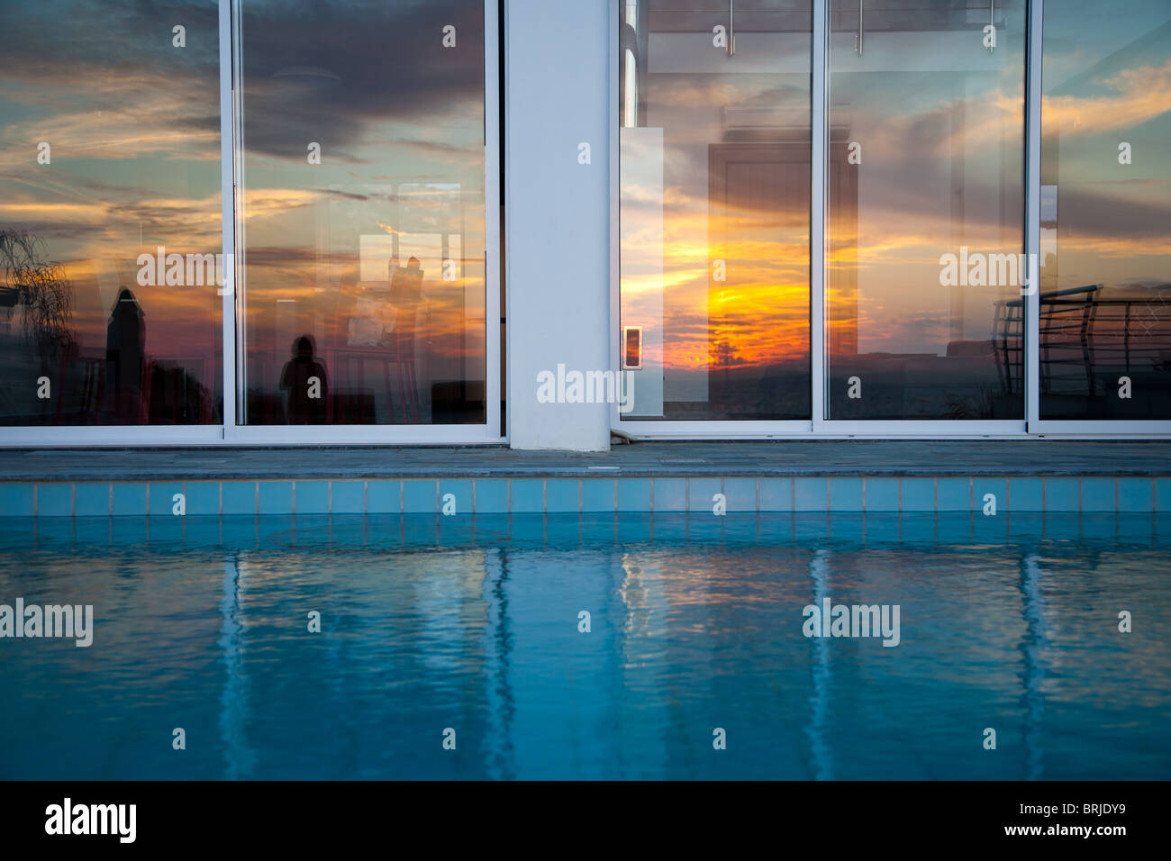 Blazing naranja atardecer reflejándose en ventanas de vidrio al lado de la  piscina Fotografía de stock - Alamy