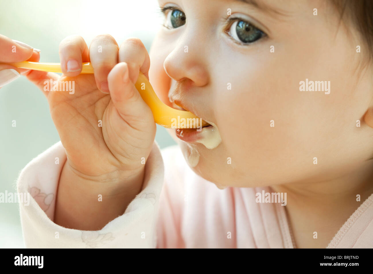 Bebé aprendiendo a comer con una cuchara Foto de stock