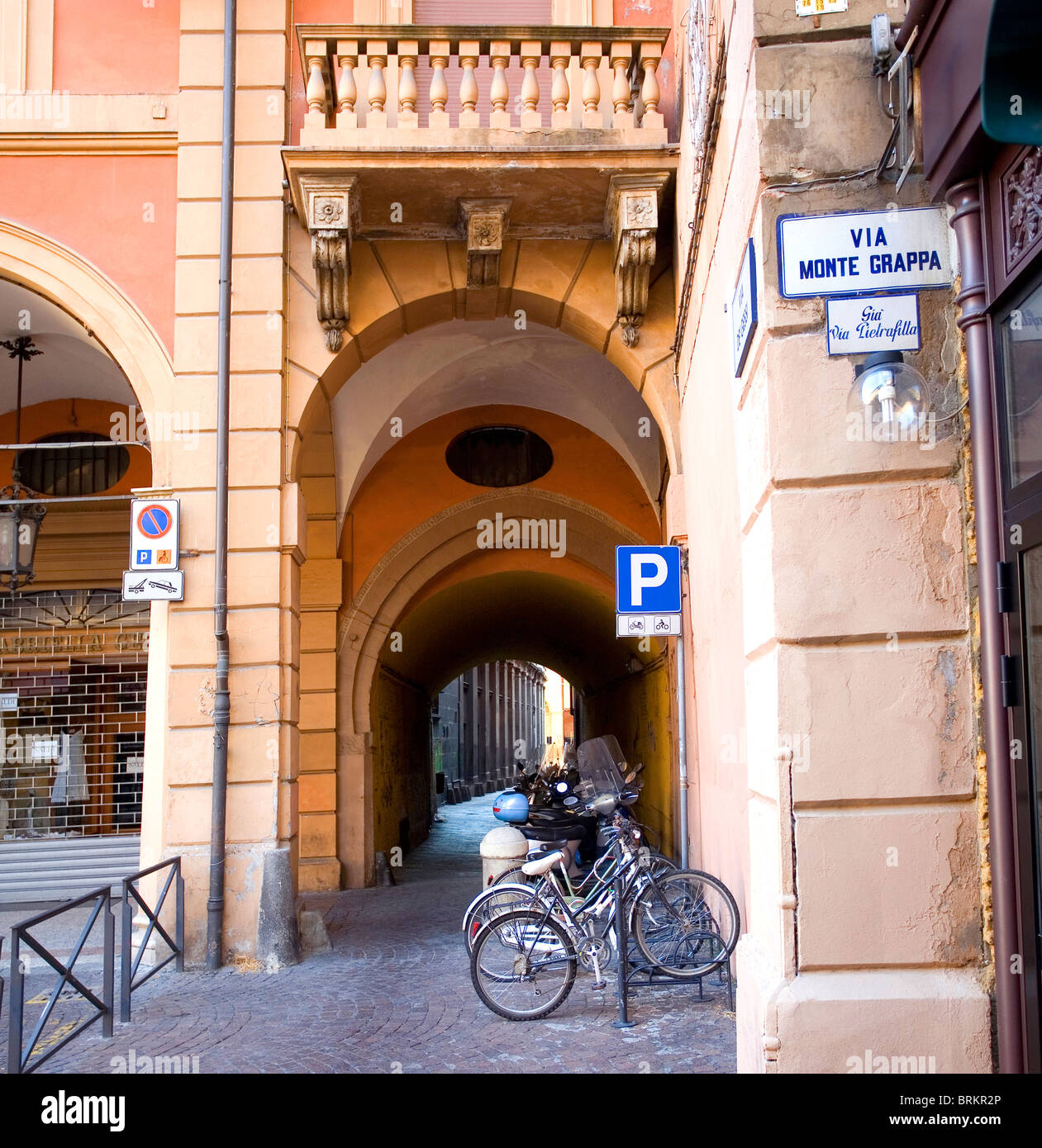 Via Monte Grappa con bicicletas aparcadas- una típica calle arqueada en Bolonia, Emilia-Romaña, Italia Foto de stock