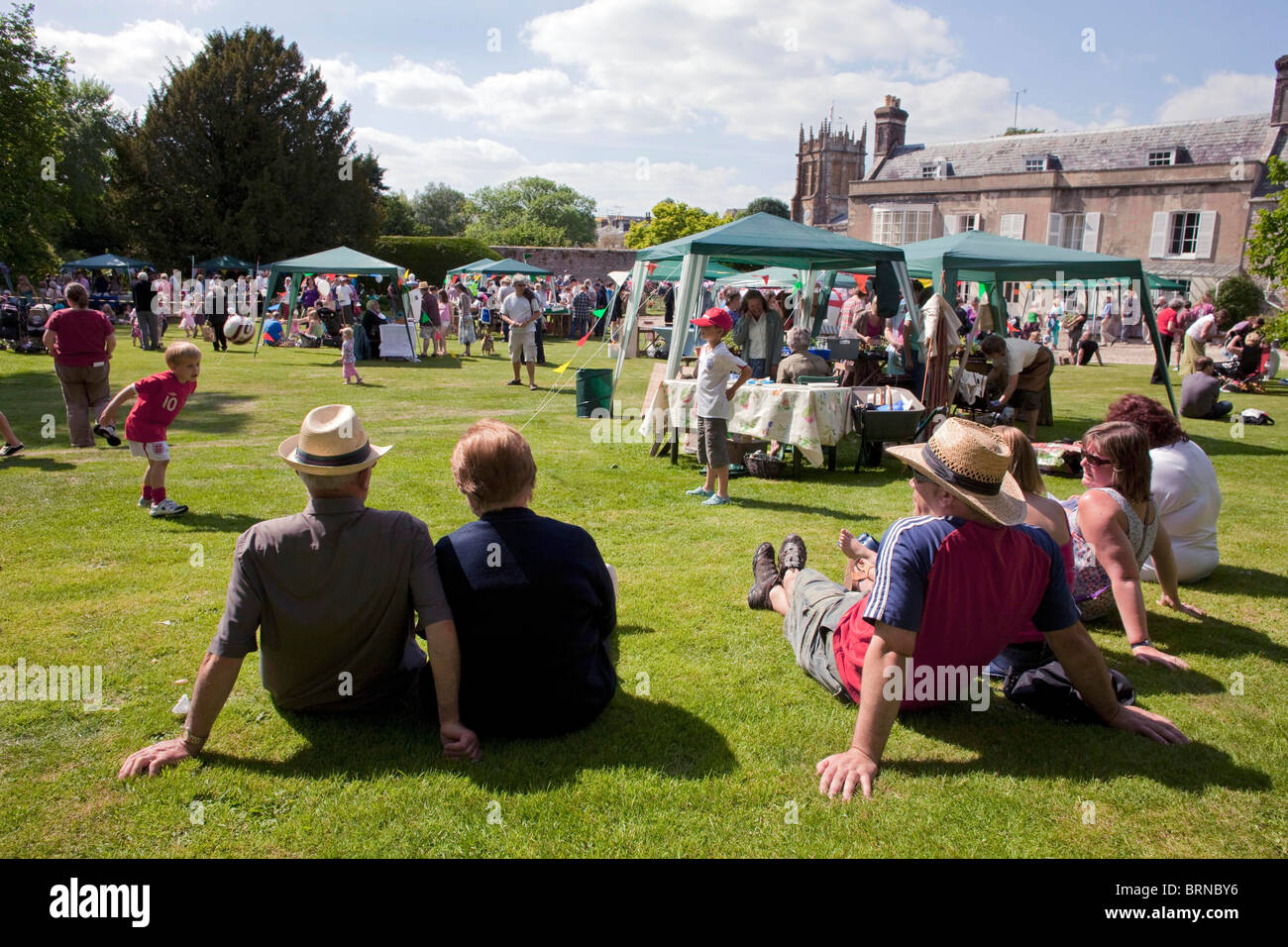 Una familia sentada en la hierba mirando el verano anual Charminster
