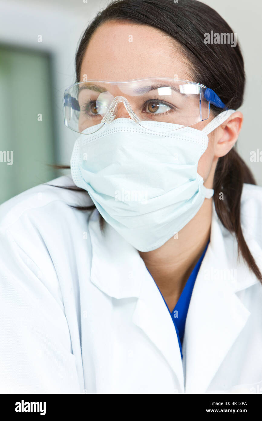 Una hembra atractiva médico o científico con una bata y mascarilla  quirúrgica y gafas de seguridad en un hospital Fotografía de stock - Alamy