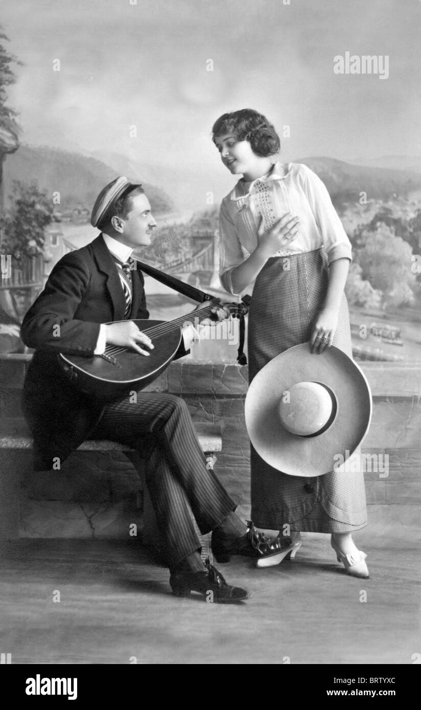 El hombre toca música para una mujer, imagen histórica, ca. 1916 Foto de stock