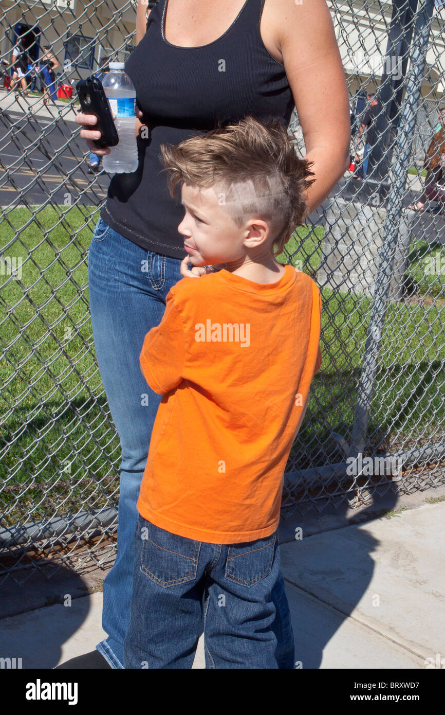 Una madre y un joven con un corte de pelo divertido en una escuela en Salida de California Foto de stock
