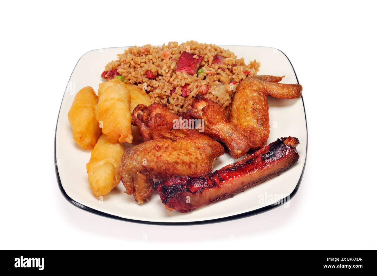 Plato de comida china de carne de cerdo con arroz frito, pollo frito crujiente dedos, alas de pollo y costillas sobre fondo blanco. Foto de stock