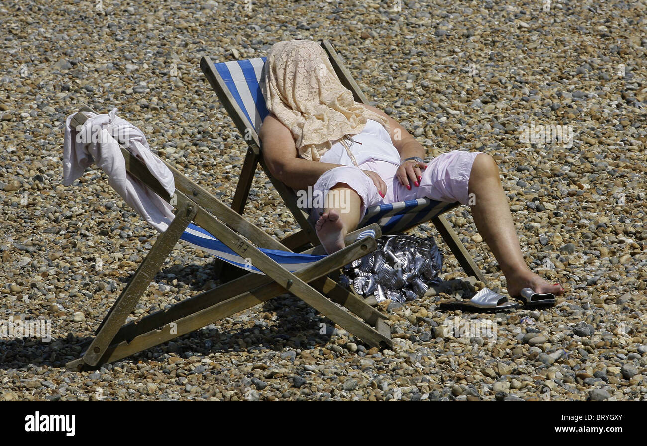 Mujer en una tumbona en la playa de Eastbourne. Fotografía por James Boardman. Foto de stock
