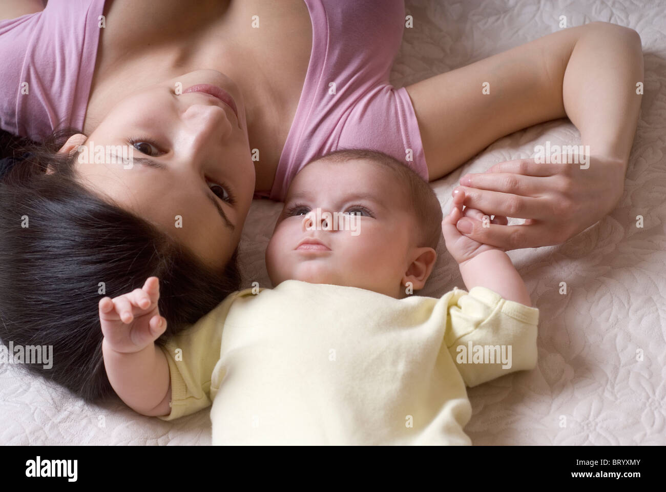 Madre sonriente tumbado con el bebé (6-11 meses) en la cama Foto de stock