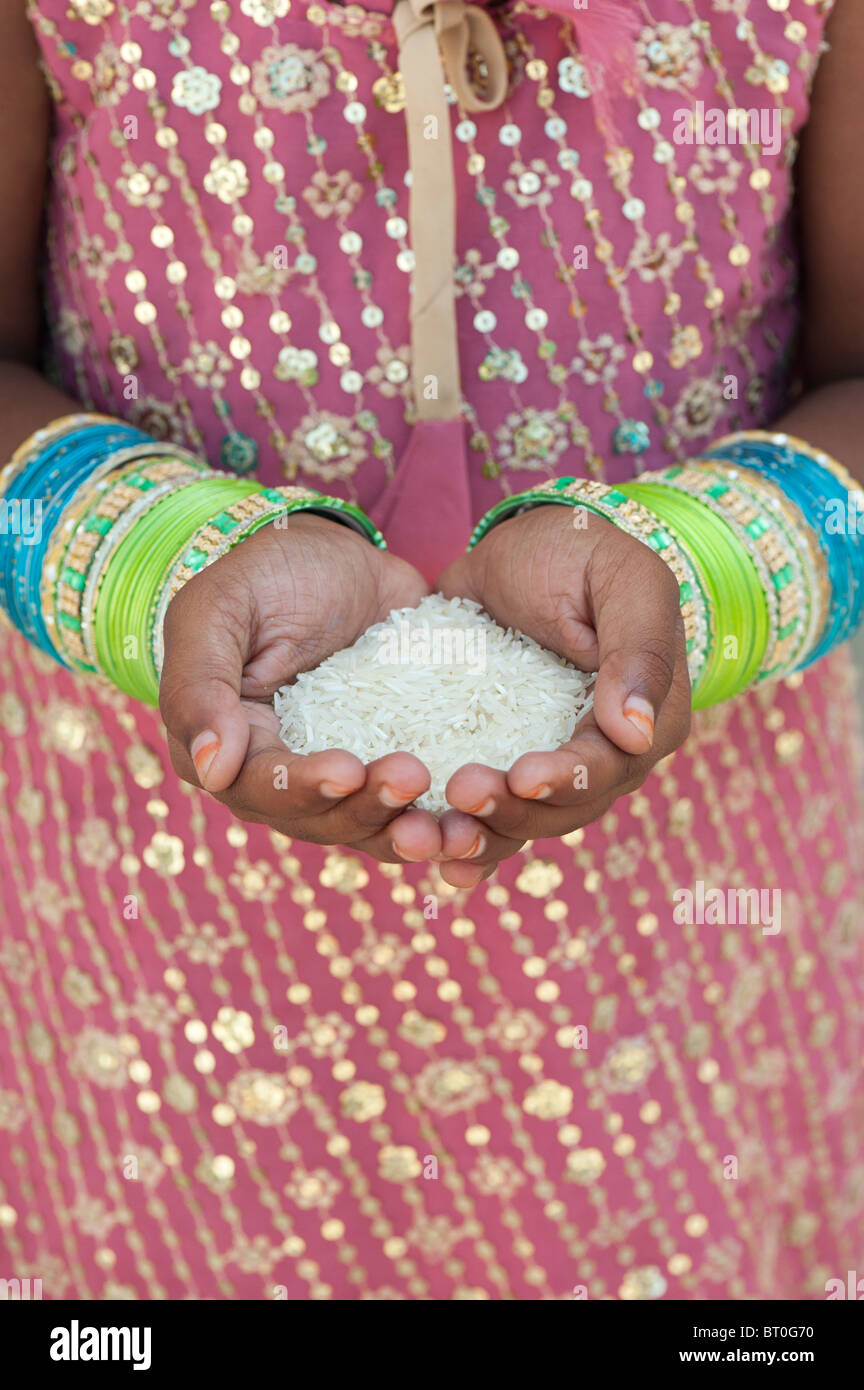 Niña india celebración arroz crudo en sus manos ahuecados. La India Foto de stock