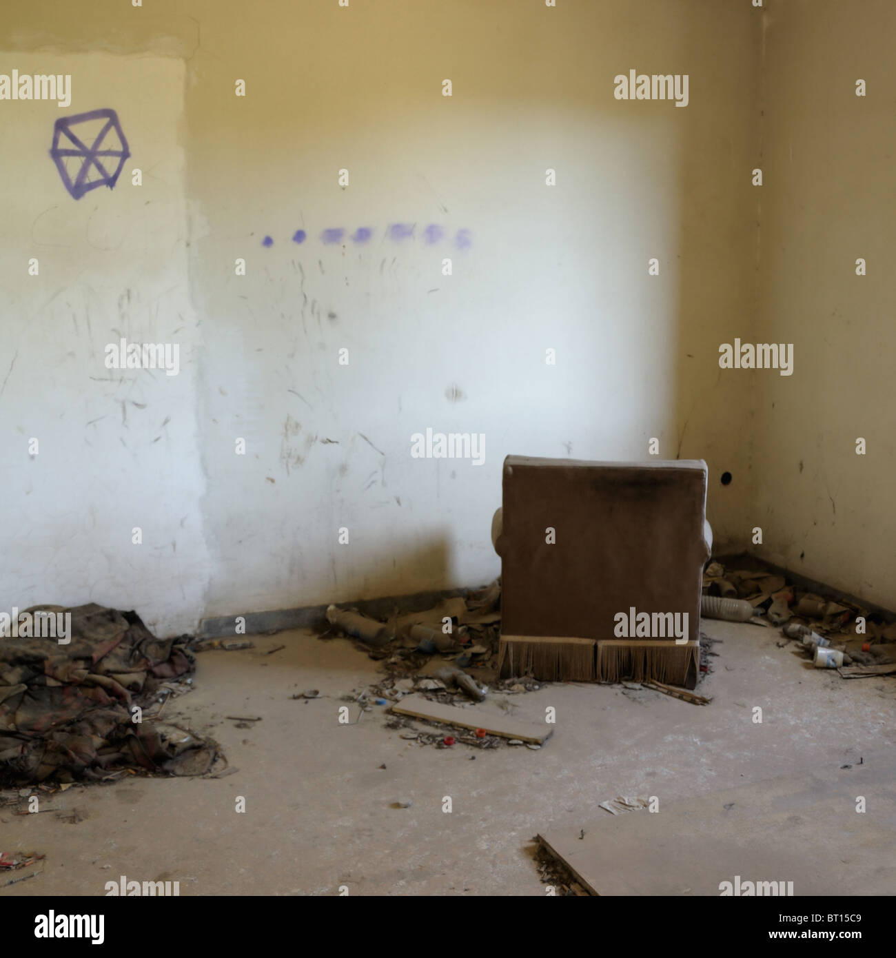 Sillón de cara a la pared en la casa abandonada. El uso de drogas de toda la parafernalia sobre el piso. Foto de stock