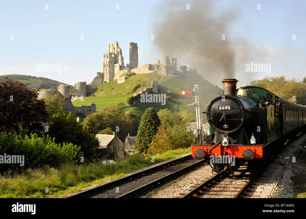 Tren de vapor con el castillo Corfe en antecedentes sobre la conservada swanage railway line Foto de stock