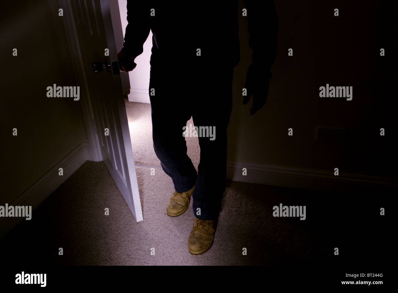 Hombre que llevaba botas viejas entrando en una habitación oscura girando  el mango mientras camina en Fotografía de stock - Alamy