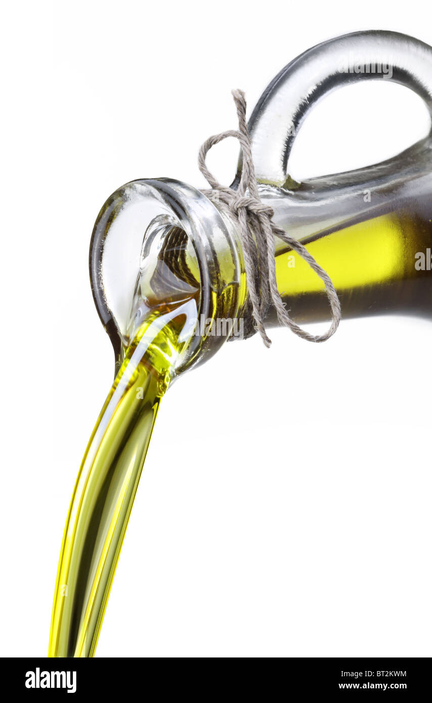 Aceite de oliva fluye desde la garrafa en la cuchara aislado en un blanco. Foto de stock