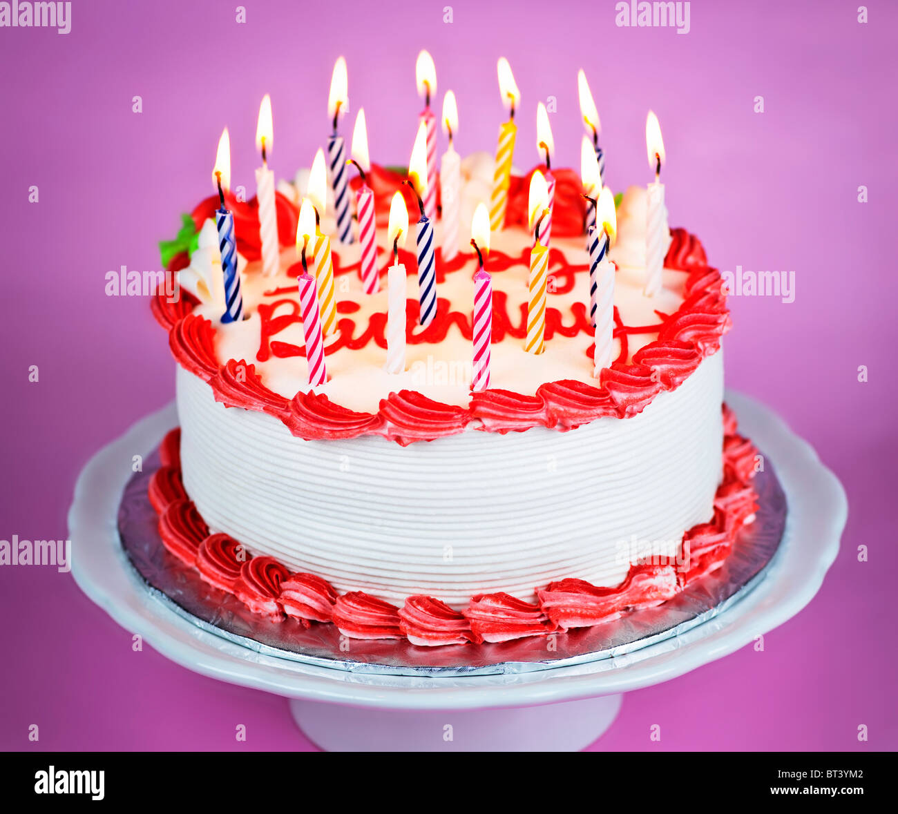 Tarta de cumpleaños con velas encendidas en una placa sobre fondo de color  rosa Fotografía de stock - Alamy