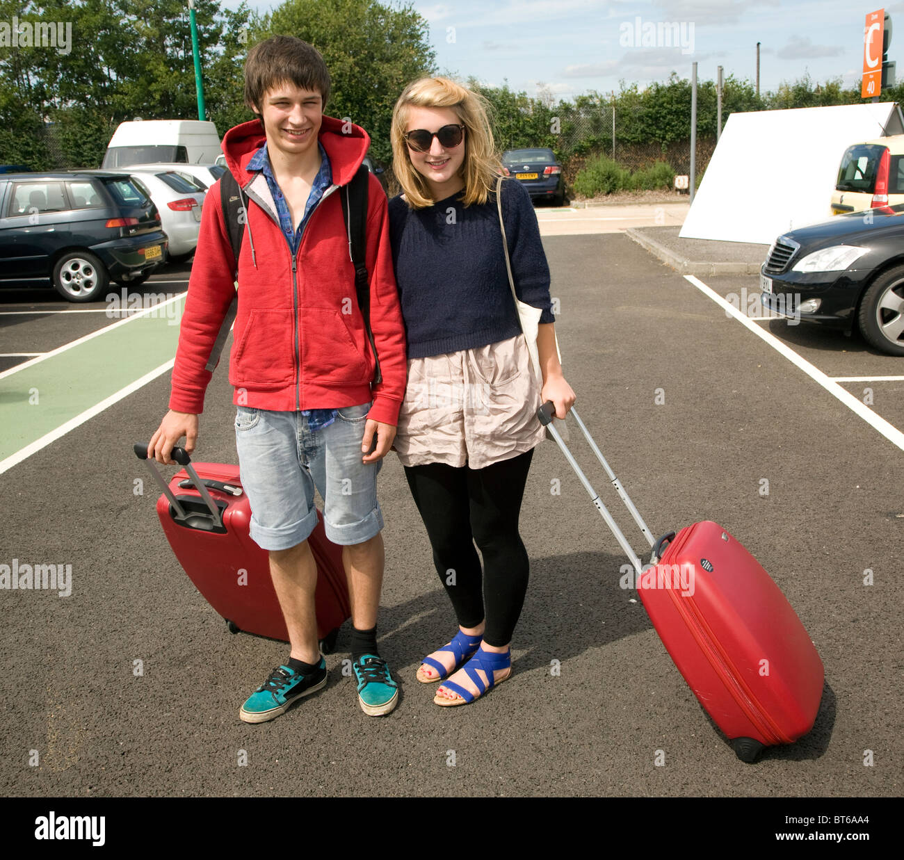 Chico y chica adolescentes gemelos con maletas rojas en el aparcamiento del  aeropuerto Fotografía de stock - Alamy