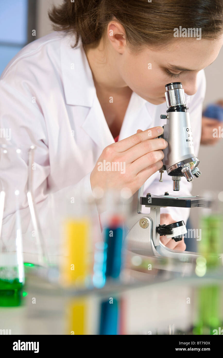 Adolescente que trabaja en un laboratorio, usando un microscopio Foto de stock