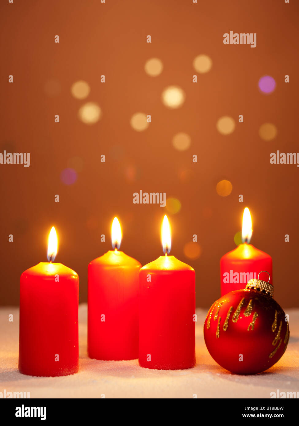 Cuatro quemando velas de adviento y un adorno de Navidad roja Foto de stock