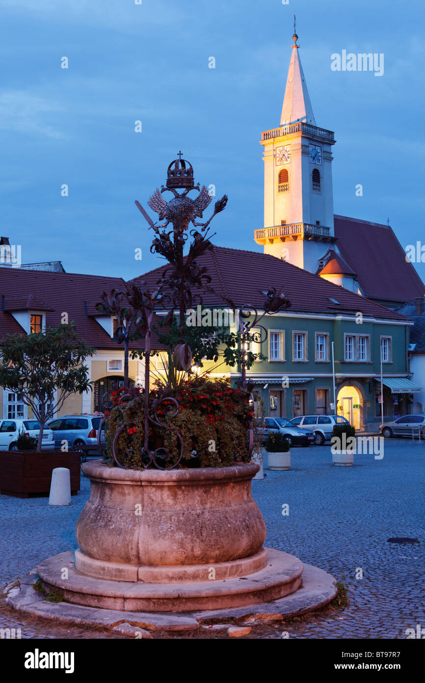 Fuente en la plaza del ayuntamiento, Iglesia Católica, óxido en el Lago Neusiedl, Burgenland, Austria, Europa Foto de stock