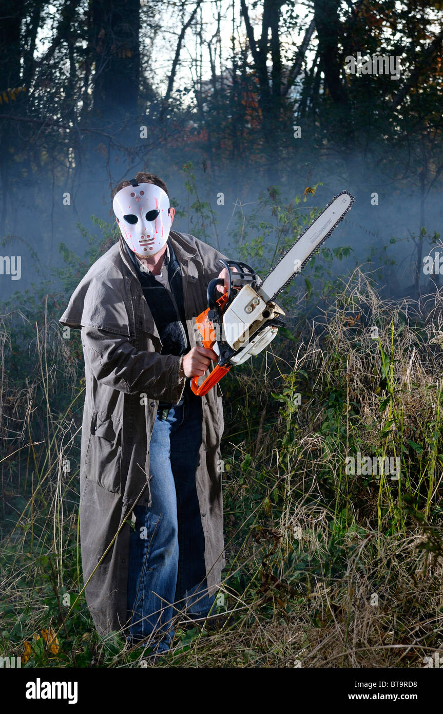 Hombre asustadizo psicópata con máscara y una motosierra en un bosque  nebuloso al atardecer en el otoño en halloween Fotografía de stock - Alamy