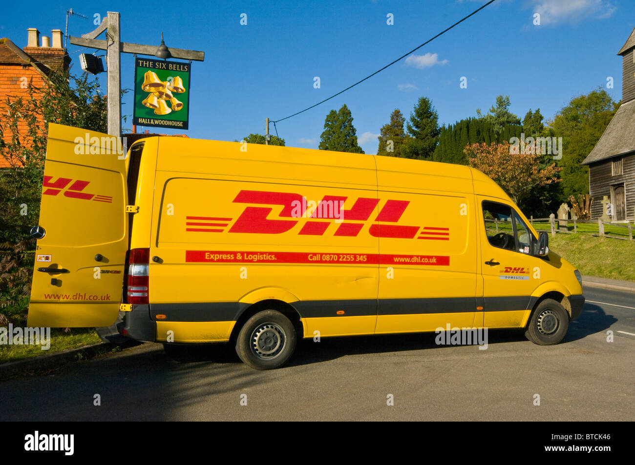 Un amarillo DHL entrega estacionada con las puertas traseras