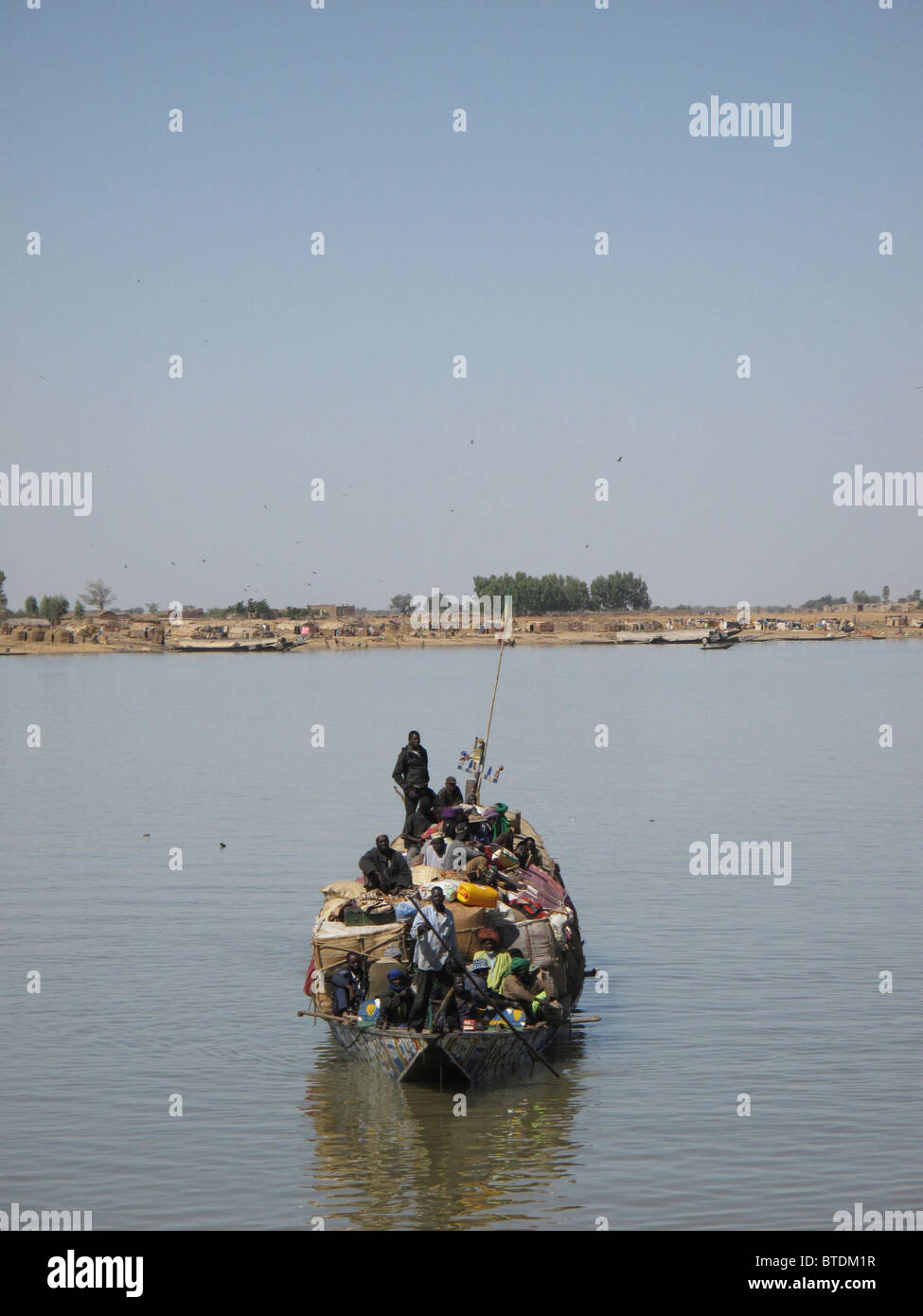 Un barco de madera cargado de pasajeros y equipaje navegando a través del agua Foto de stock