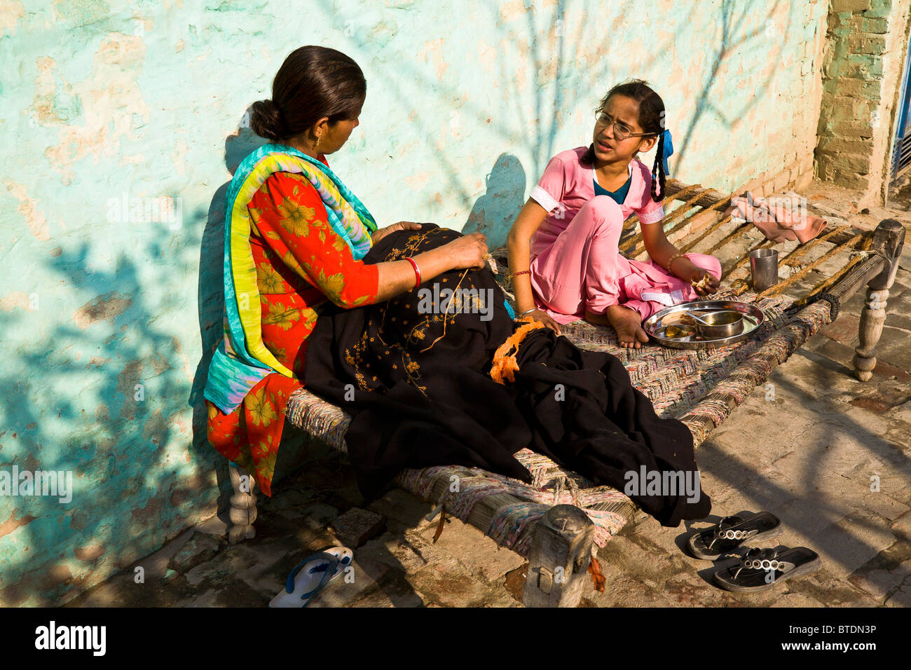 Jasbir Kaur y su madre se sientan en el otoño tardío sol hablando como Jasbir se sienta a finales de merienda como madre cose. Foto de stock