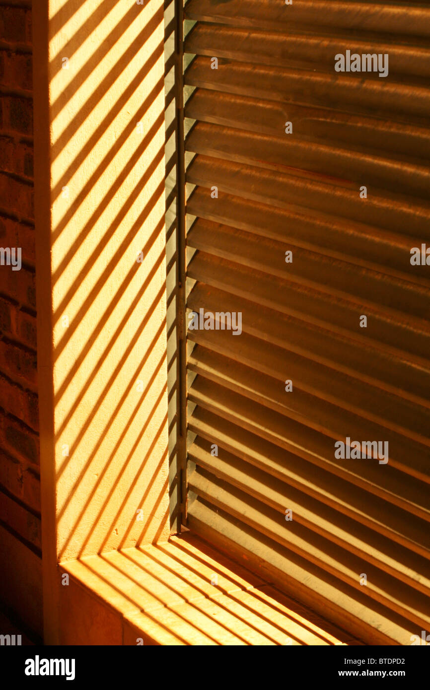 Las persianas de madera de ventana con el sol brillando a través de Foto de stock