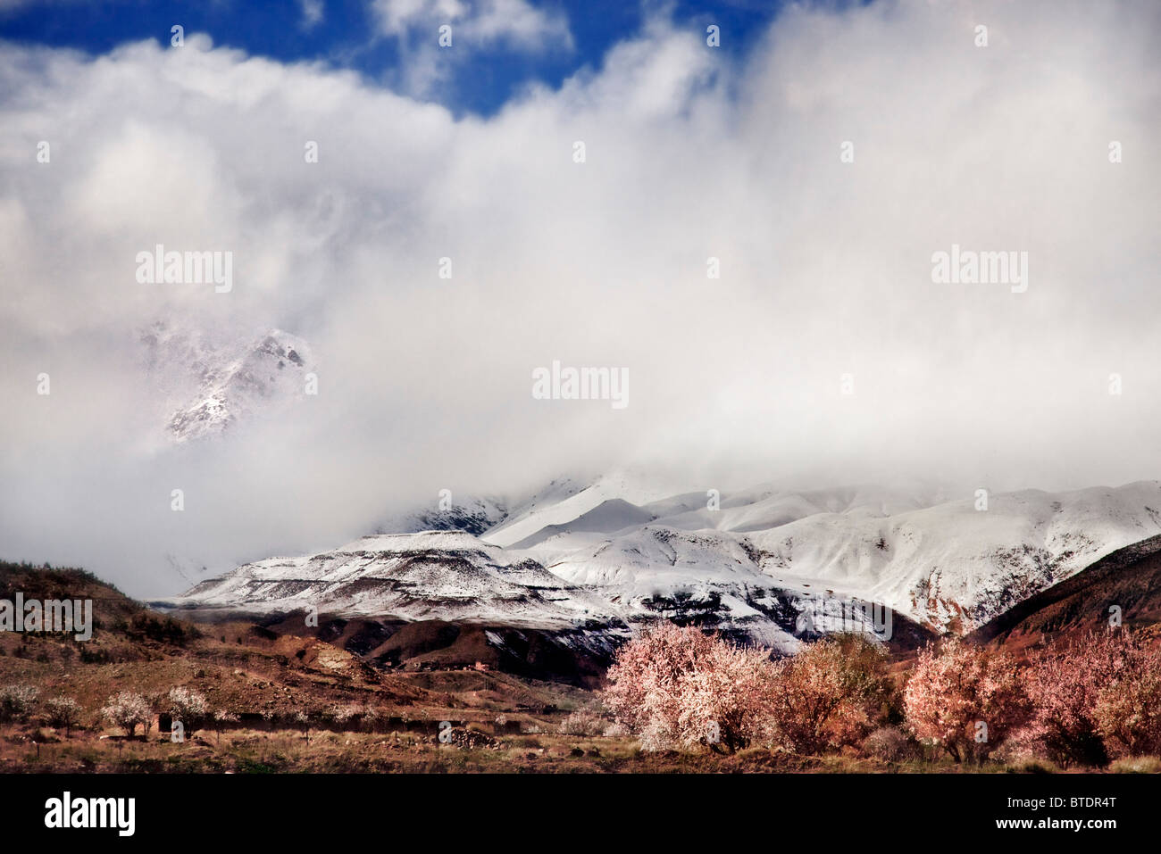 La cobertura de nubes por encima de los picos nevados de las montañas del Alto Atlas Foto de stock