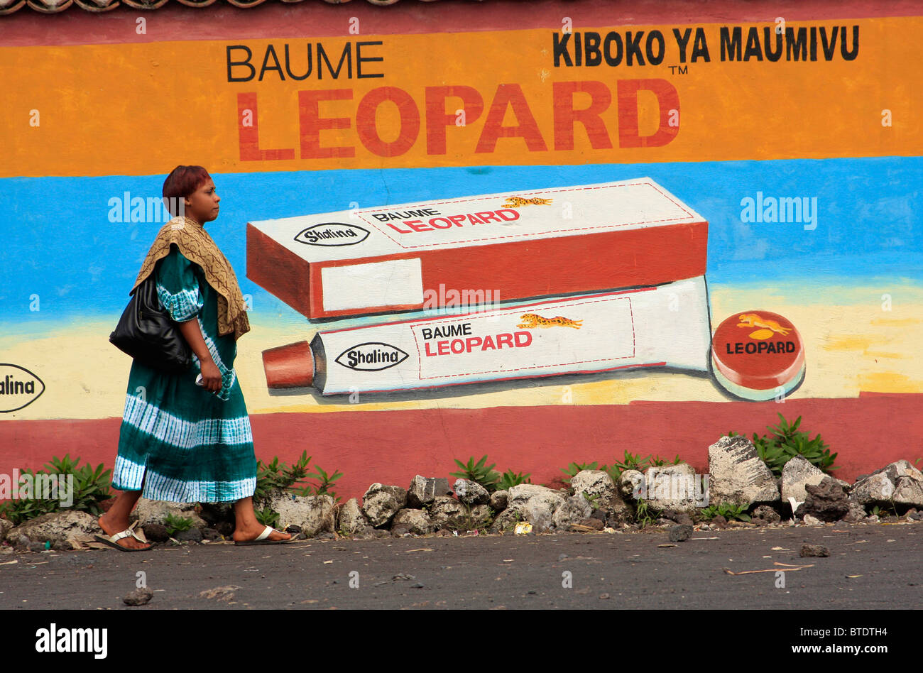 Mujer caminando por un colorido mural de publicidad Foto de stock