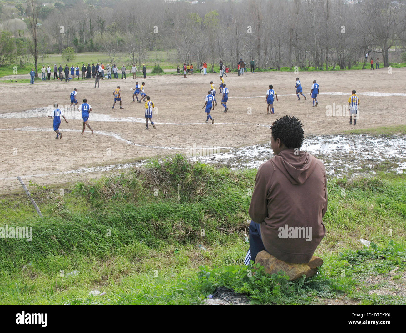 Joven viendo un partido de fútbol en un campo anegado Foto de stock