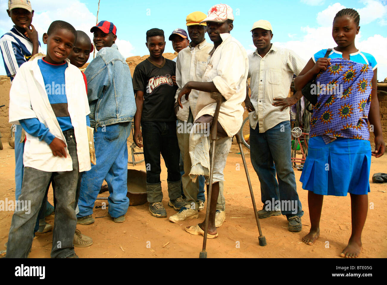 Grupo de personas en la carretera en el sur de Angola, incluido un hombre con muletas que tenía una pierna volado por una mina terrestre Foto de stock