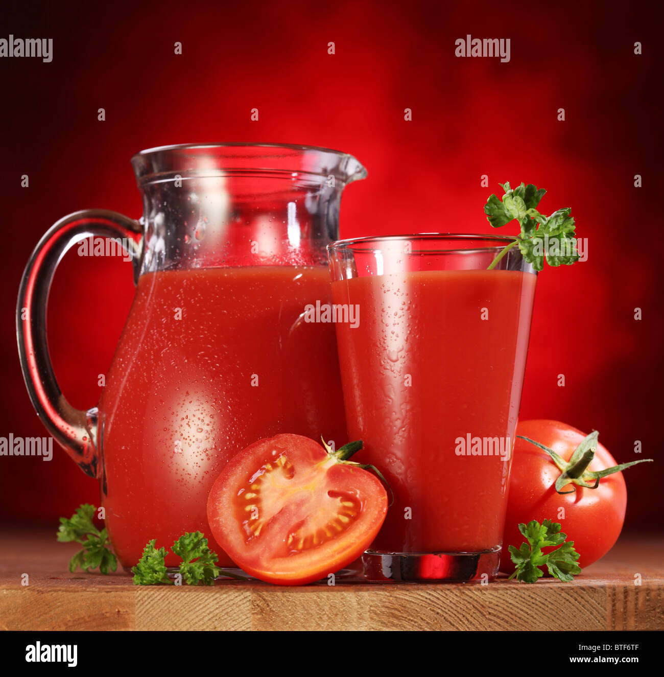 Still life: tomates, jarra y vaso lleno de zumo de tomate fresco sobre la mesa de madera. Foto de stock