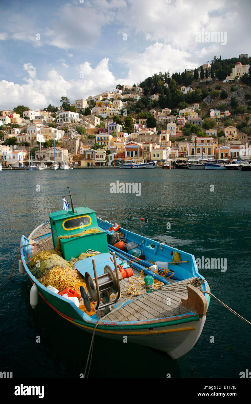 Barco de pesca en el puerto con casas neoclásicas, Symi, Grecia. Foto de stock