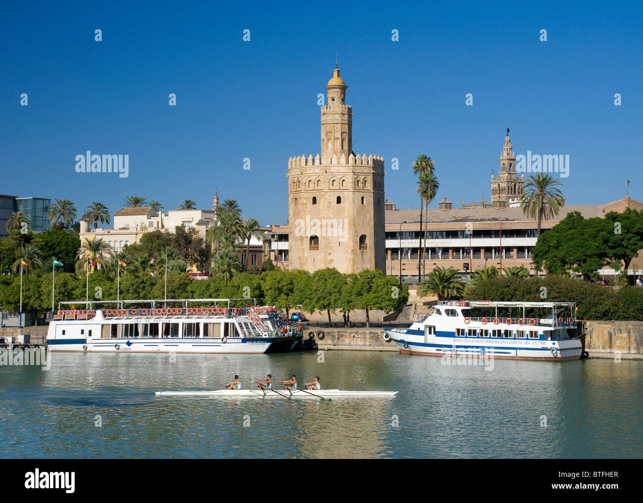 España, Sevilla, la Torre del Oro, la Torre del Oro, los barcos de crucero y una canoa en el río Guadalquivir Foto de stock