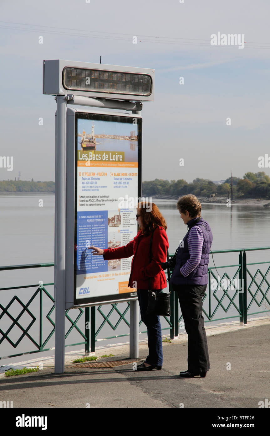 Las mujeres leyendo un ferry information board junto al río Loira en Le Pellerin cerca de Nantes, Francia Foto de stock