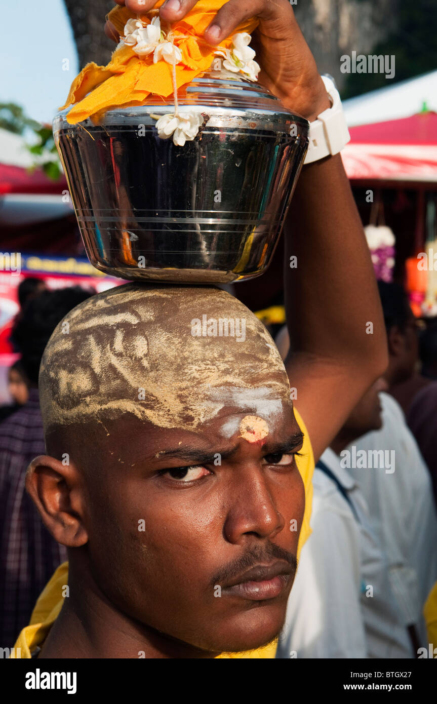 Devoto hindú portando una lota con agua durante el festival Thaipusam en las Cuevas Batu. Foto de stock