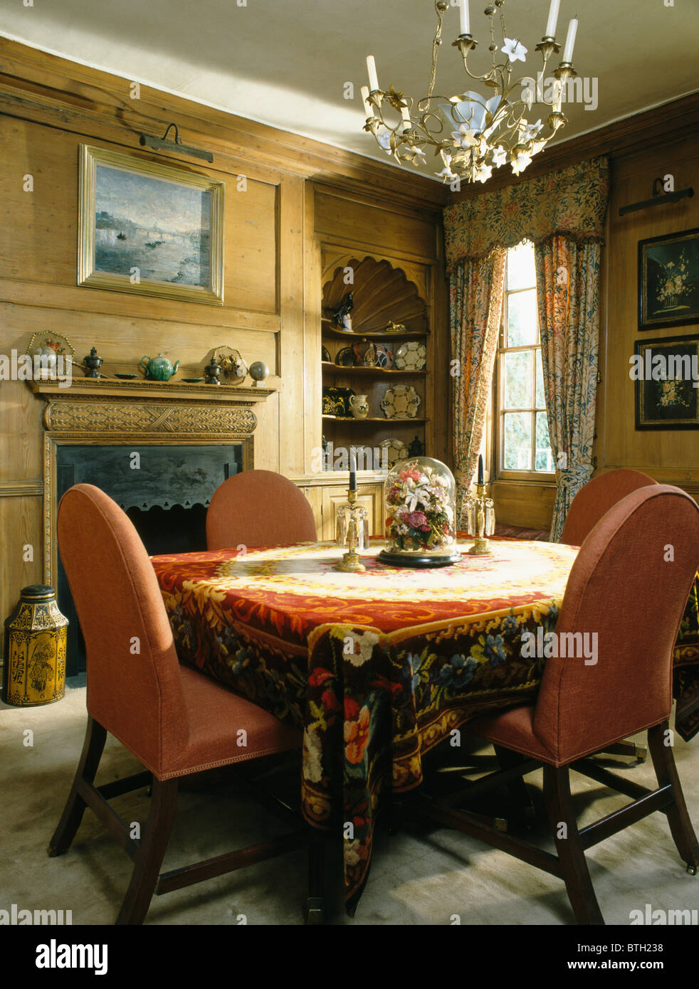 Sillas tapizadas de color terracota a la mesa con tela de chenilla rojo  pequeño comedor con paneles de madera Fotografía de stock - Alamy